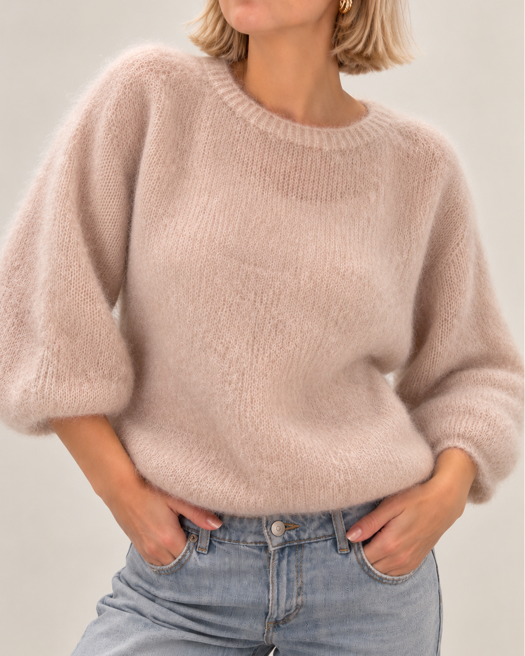 Beige vajaahihainen kid mohairneule mallin päällä. Pehmeä ja pörröinen naisten neule, jossa on pyöreä pääntie, ribbineulotut reunat ja rento istuvuus.