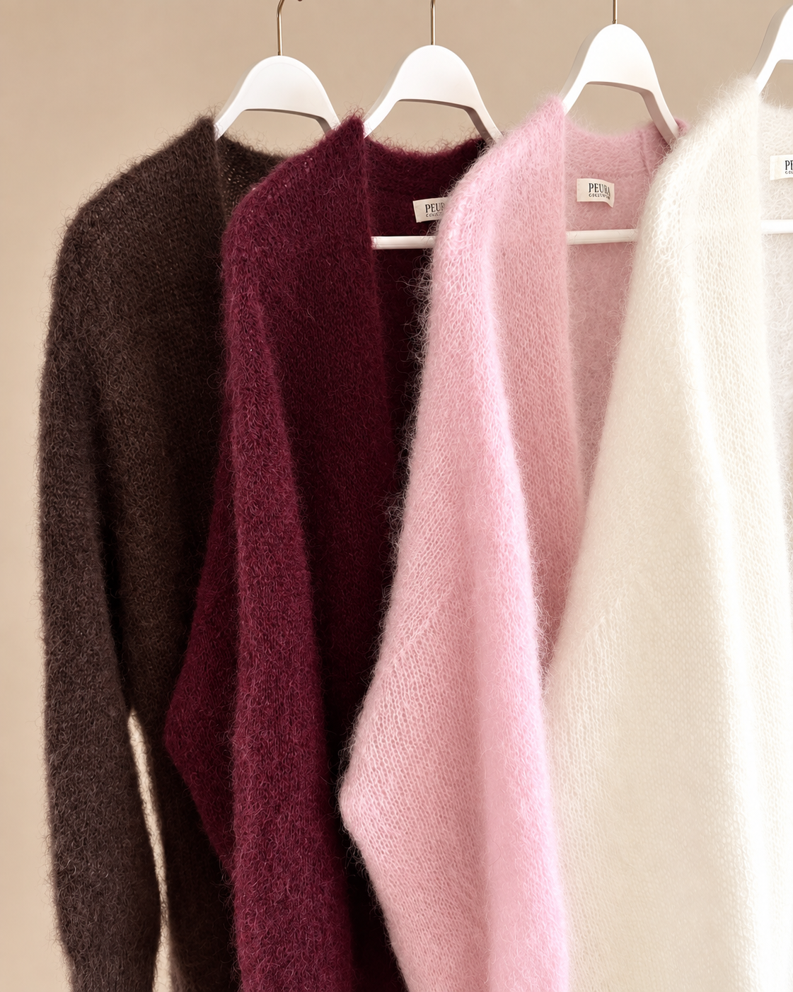 Lähikuvia Lilja pitkistä Kid Mohair neuletakeista henkareilla tummanruskeana, viininpunaisena, vaaleanpunaisena ja luonnonvalkoisena.